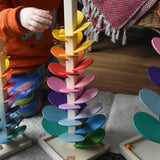 Magic Wood small 48cm marble tree with a child's hand placing a yellow glass marble on one of the top rungs. 