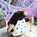 A felted mole figure wearing a spotty apron holding a bucket and a mop. The figure has been created using The Makerss Small Busy Mr Mole Needle Felt Kit.
