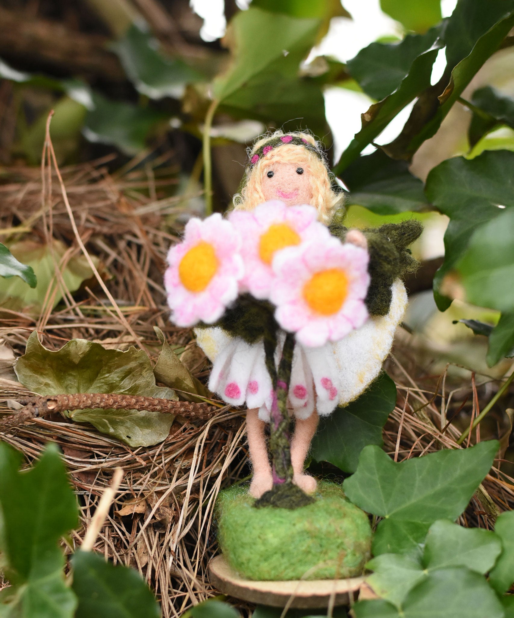 A Daisy flower fairy placed on an ivy covered tree branch. The fairy has been made using The Makerss Official Flower Fairies Daisy Fairy Needle Felt Kit.