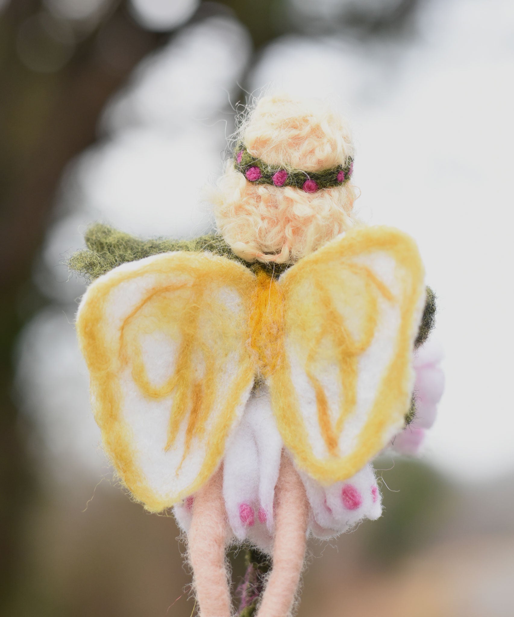A close up of a felted Daisy flower fairy's wings showing the yellow coloured detailing on the white wings. The fairy has been made using The Makerss Official Flower Fairies Daisy Fairy Needle Felt Kit.