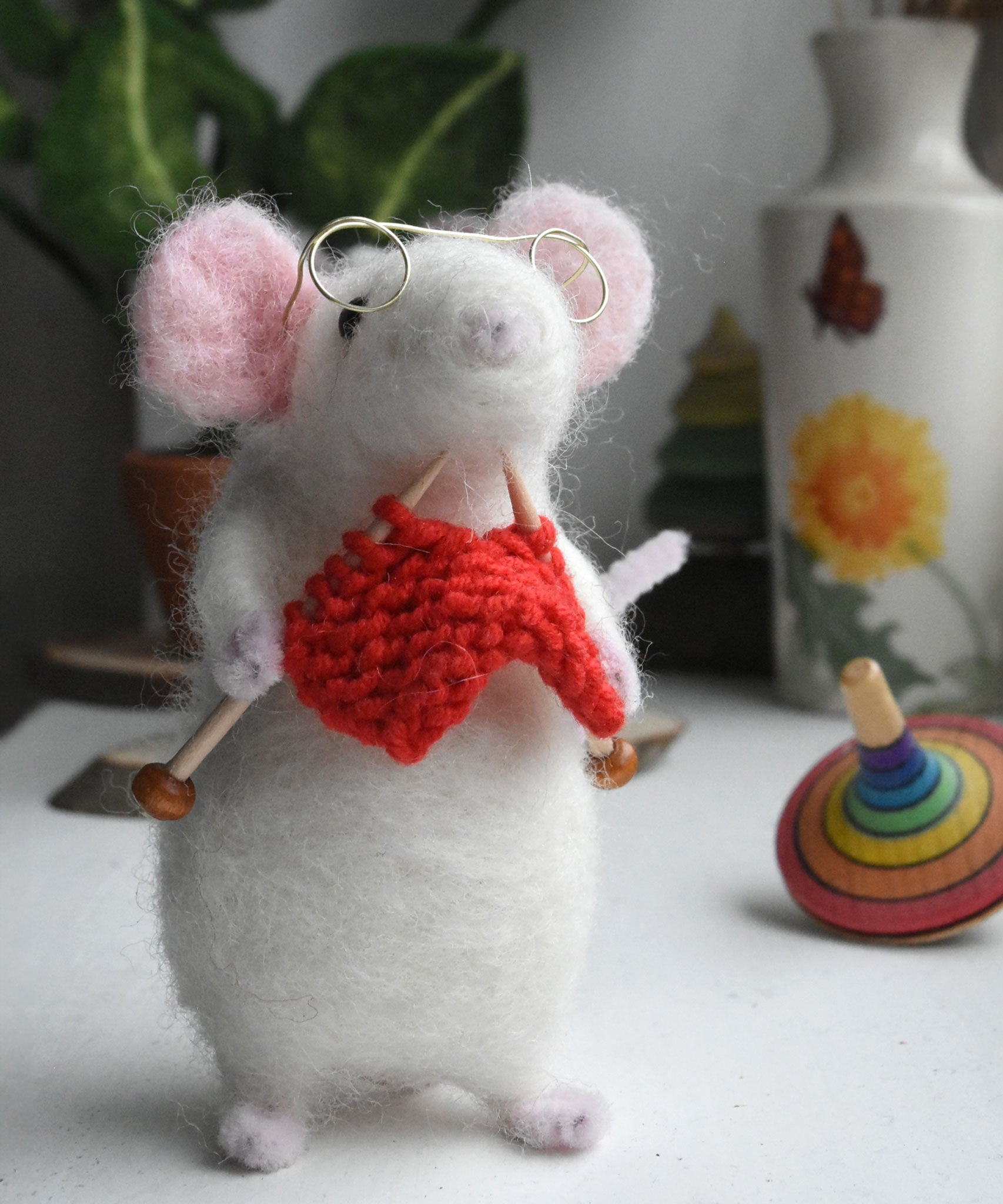 A felt figure of a mouse nitting made using the Makerss Small Knitting Mouse Needle Felt Kit.