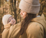 A close up of a woman and baby wearing the Mamalila Allweather Cosy Allrounder Babywearing Jacket in a Mustard yellow colour.