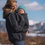A person wearing the Mamalila Outdoor Explorer Babywearing Jacket - Mint