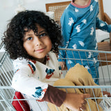 Child sitting in a trolley wearing the Maxomorra organic cotton long sleeved viking print top with mustard yellow trousers. 