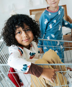 Child sitting in a trolley wearing the Maxomorra organic cotton long sleeved viking print top with mustard yellow trousers. 