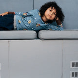 Child wearing the Maxomorra GOTS organic cotton long sleeve top in blue with a cute repeating owl print and brown neck line and cuffs.