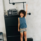 Child wearing the Maxomorra kids GOTS organic cotton boxer shorts in a blue, white, yellow and brown striped design with a blue vest top.
