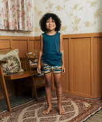 Child wearing the Maxomorra kids GOTS organic cotton boxer shorts in a blue, white, yellow and brown striped design with a blue vest top.