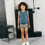 Child wearing the Maxomorra kids GOTS organic cotton boxer shorts in a blue, white, yellow and brown striped design with a blue vest top.