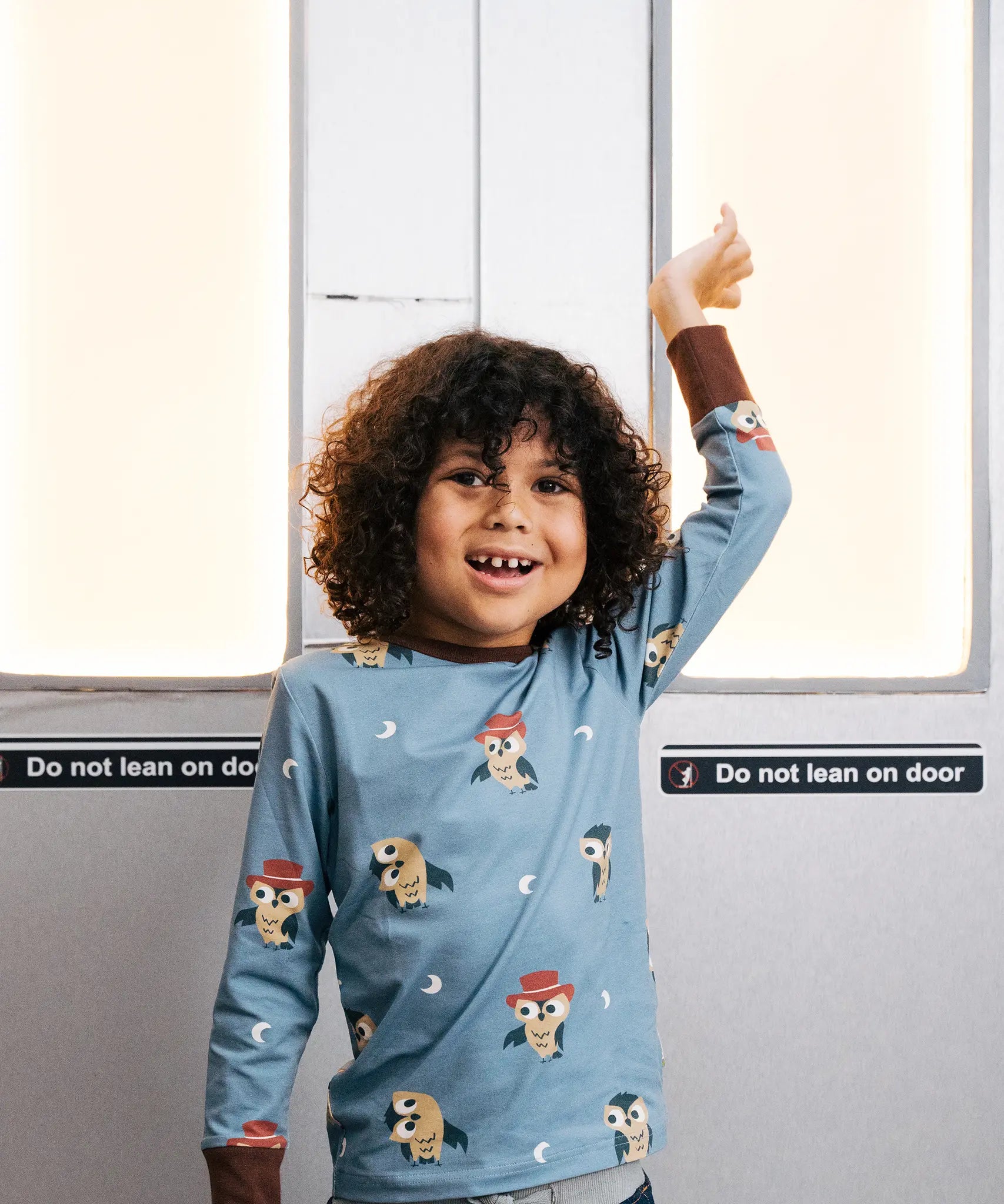 Child wearing the Maxomorra GOTS organic cotton long sleeve top in blue with a cute repeating owl print and brown neck line and cuffs.