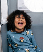 Child smiling wearing the Maxomorra GOTS organic cotton long sleeve top in blue with a cute repeating owl print and brown neck line and cuffs.