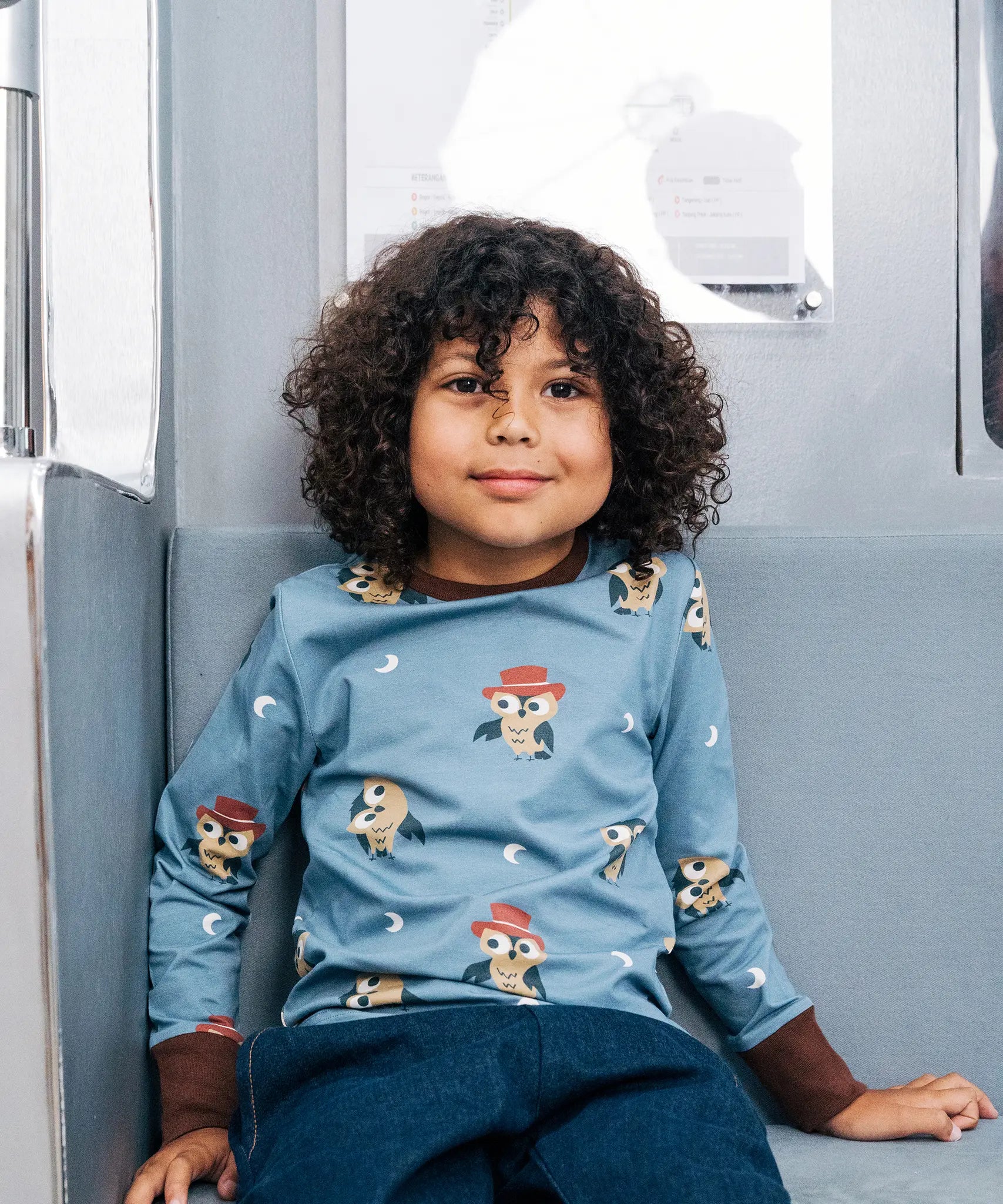 Child wearing the Maxomorra GOTS organic cotton long sleeve top in blue with a cute repeating owl print and brown neck line and cuffs.
