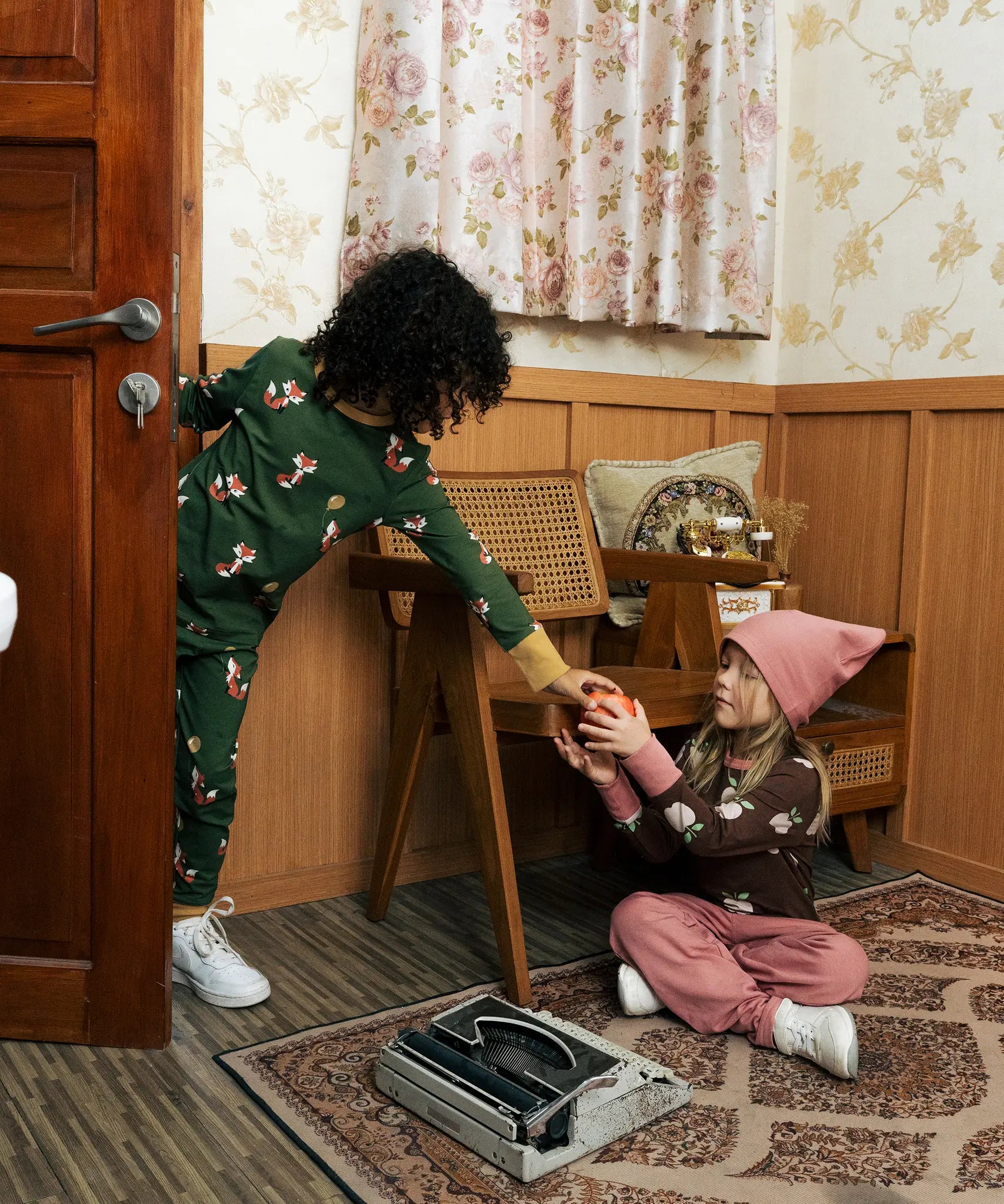 Two children wearing Maxomorra organic cotton clothing. one wearing green fox print long sleeve top one wearing the brown apple print top with ink trousers. 