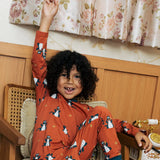 Child wearing the Maxomorra kids dragons organic cotton long sleeve top with pyjama trousers. Red top with repeat blue dragon print and blue arm cuffs and binding on the neck. 
