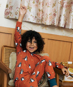 Child wearing the Maxomorra kids dragons organic cotton long sleeve top with pyjama trousers. Red top with repeat blue dragon print and blue arm cuffs and binding on the neck. 
