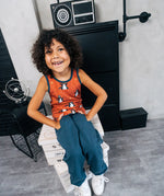 Child wearing the Maxomorra kids dragons organic cotton sleeveless vest with blue teal joggers. Rust red sleeveless vest top with repeat print featuring a blue dragon and yellow fire outlines with blue binding on the neck and arm holes. 
