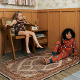 Two Children wearing Maxomorra organic cotton clothing. One is wearing a brown apple print vest and shorts the other is wearing a rust red blue dragon print long sleeved top with matching trousers.