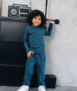 Child wearing the Maxomorra organic cotton kids baggy sweat pants in blue, features a drawstring cord around the waist and side pockets with matching long sleeved top.