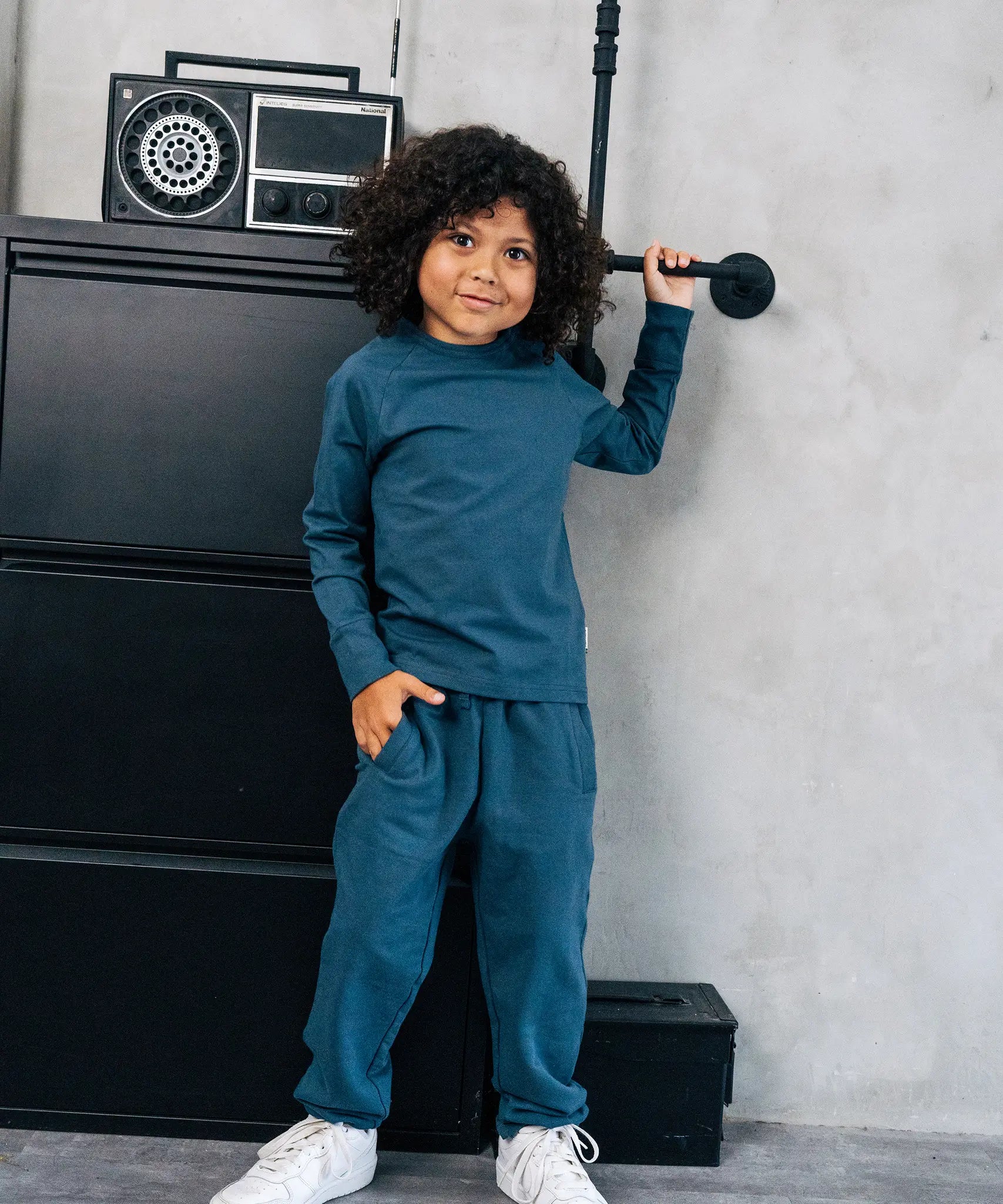 Child wearing the Maxomorra organic cotton kids baggy sweat pants in blue, features a drawstring cord around the waist and side pockets with matching long sleeved top.