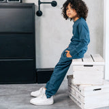 Child wearing the Maxomorra kids baggy sweat pants in blue, features a drawstring cord around the waist and side pockets with matching long sleeved top.