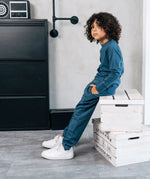 Child wearing the Maxomorra kids baggy sweat pants in blue, features a drawstring cord around the waist and side pockets with matching long sleeved top.