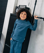 Child wearing the Maxomorra organic cotton kids baggy sweat pants in navy, features a drawstring cord around the waist and side pockets with matching long sleeved top.
