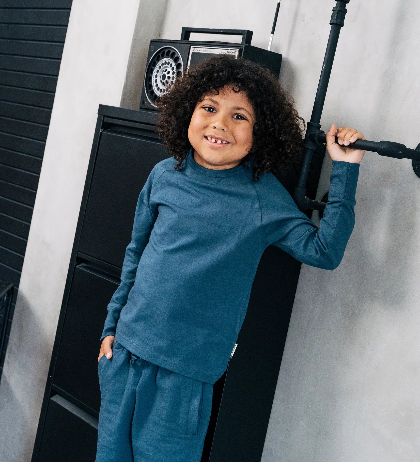 Child wearing the Maxomorra organic cotton kids baggy sweat pants in navy, features a drawstring cord around the waist and side pockets with matching long sleeved top.