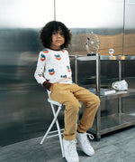 Child wearing the Maxomorra kids vikings organic cotton long sleeve top with mustard yellow trousers. Light coloured top with  repeat viking print and contrasting brown arm cuffs and binding on the neck. 
