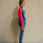 A side view of a child wearing a Maxomorra Reindeer Raglan Long Sleeve Top with reindeer print leggings. 