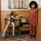 Two Children wearing Maxomorra organic cotton clothing. One is wearing a brown apple print vest and shorts the other is wearing a rust red blue dragon print long sleeved top with matching trousers.