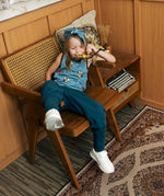 Child wearing the Maxomorra GOTS organic cotton kids tank vest top in blue with a cute repeating owl print and brown trim.with blue trousers.
