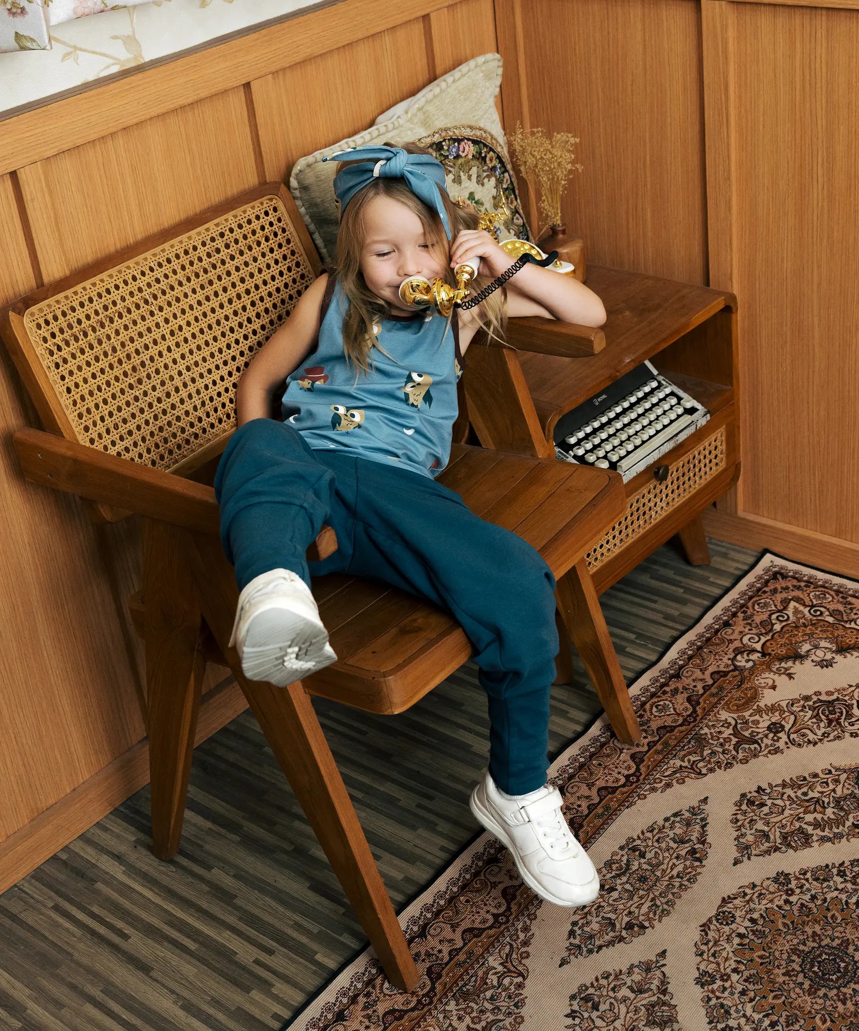 Child wearing the Maxomorra GOTS organic cotton kids tank vest top in blue with a cute repeating owl print and brown trim.with blue trousers.