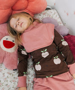 Child wearing the Maxomorra GOTS organic cotton long sleeve top in brown with a cute repeating pink apple print and pale pink neck line and cuffs with a pink snood bib scarf.