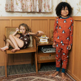 Two Children wearing Maxomorra organic cotton clothing. One is wearing a brown apple print vest and shorts the other is wearing a rust red blue dragon print long sleeved top with matching trousers.