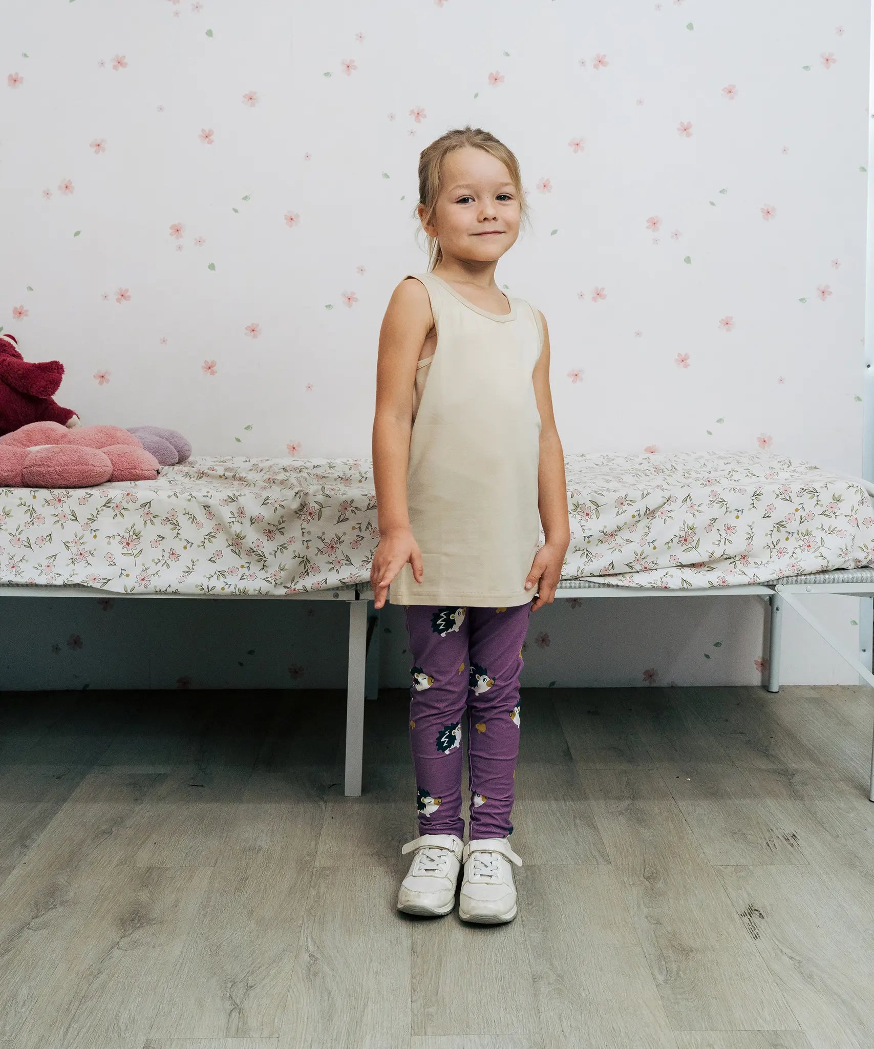 Girl wearing the Maxomorra kids GOTS organic cotton leggings in purple with a repeating cute hedgehog print and elasticated waist band with a cream vest top.