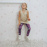 Girl wearing the Maxomorra kids GOTS organic cotton leggings in purple with a repeating cute hedgehog print and elasticated waist band with a cream vest top.