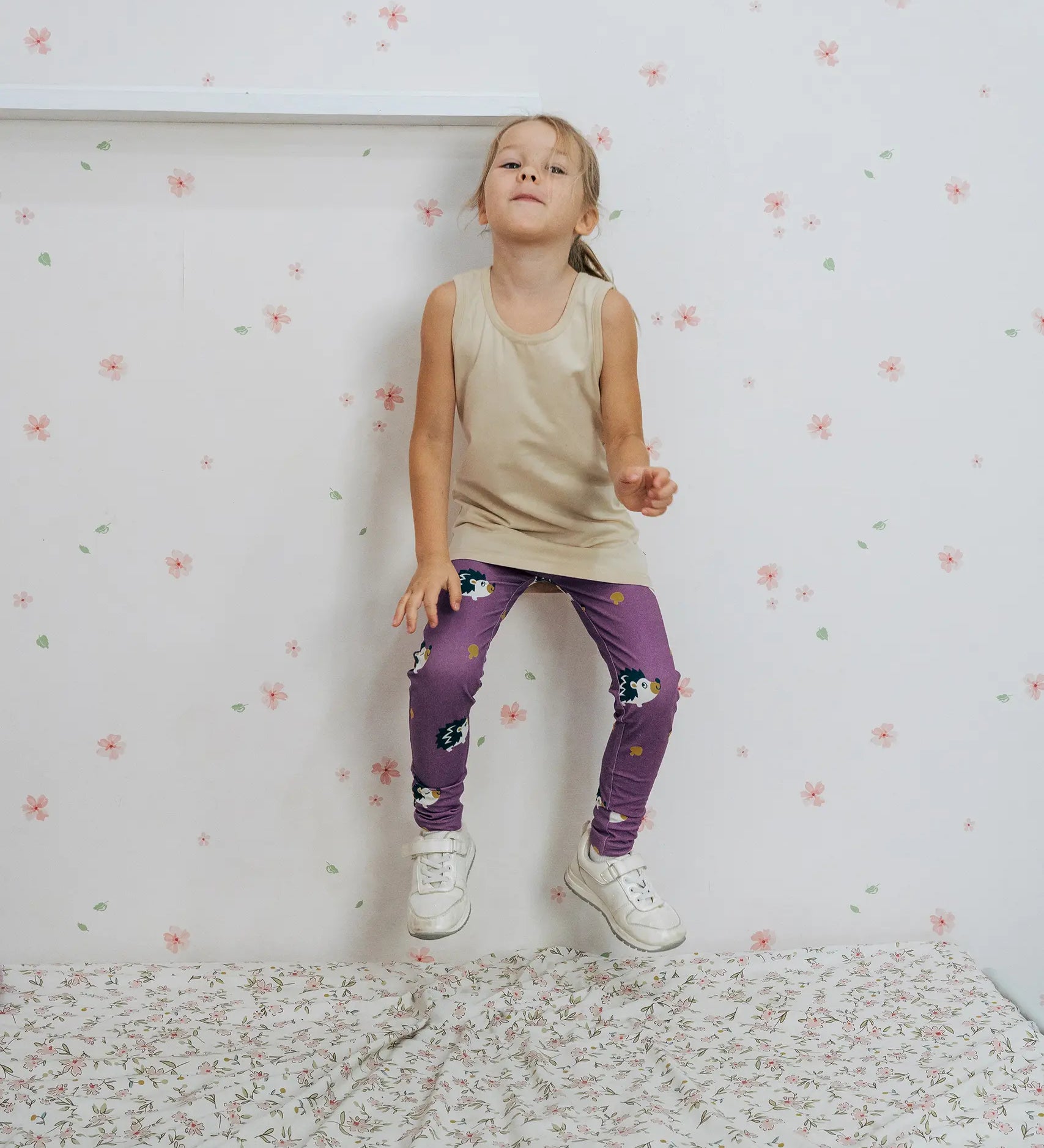 Girl wearing the Maxomorra kids GOTS organic cotton leggings in purple with a repeating cute hedgehog print and elasticated waist band with a cream vest top.