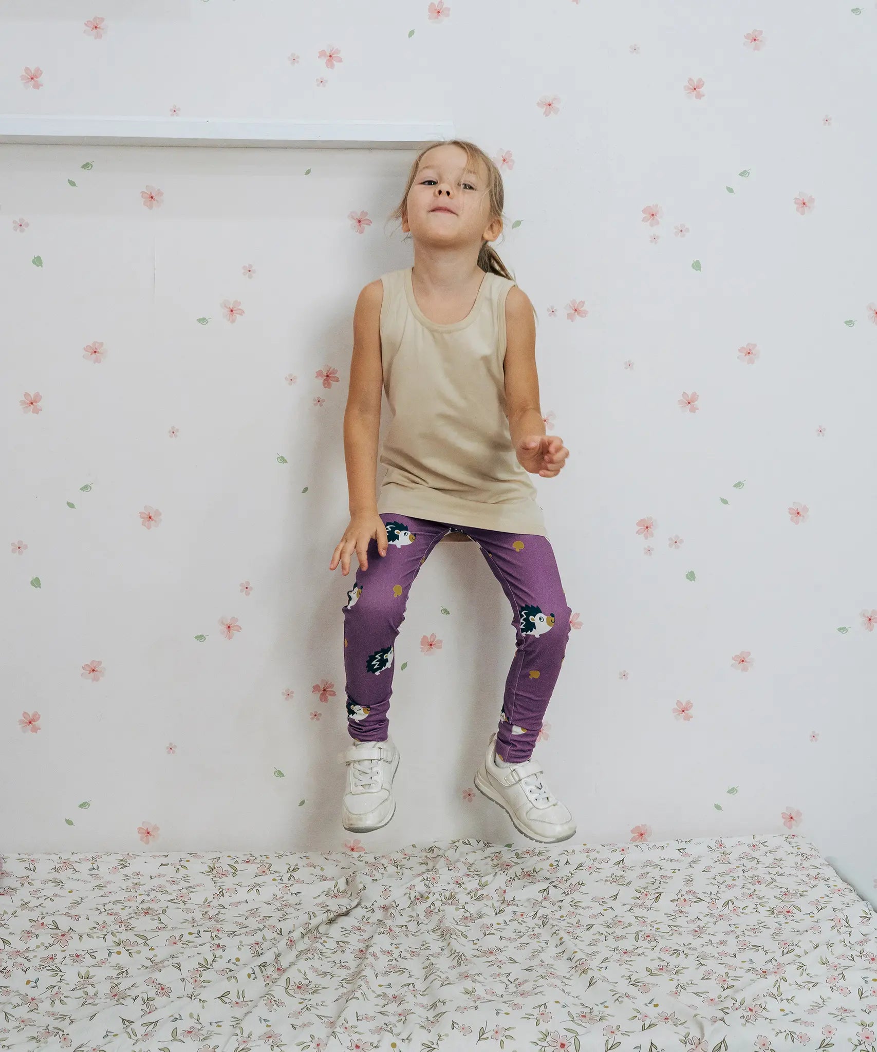 Girl wearing the Maxomorra kids GOTS organic cotton leggings in purple with a repeating cute hedgehog print and elasticated waist band with a cream vest top.