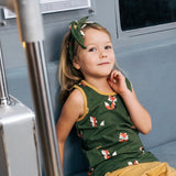 Child wearing the Maxomorra kids organic cotton green fox print vest with yellow trousers sitting on a train.