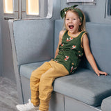 Child wearing the Maxomorra kids organic cotton green fox print vest with yellow trousers sitting on a train.