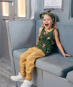 Child wearing the Maxomorra kids organic cotton green fox print vest with yellow trousers sitting on a train.