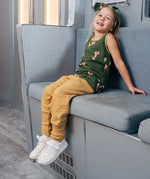 Child wearing the Maxomorra kids organic cotton green fox print vest with yellow trousers sitting on a train.