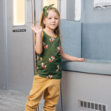 Child wearing the Maxomorra kids organic cotton green fox print vest with yellow trousers standing on a train.