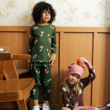 Child wearing Maxomora organic cotton green long-sleeve top with all over red fox print with matching pyjama trousers. Another child in background wearing brown apple print top with pink trousers. 