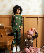 Child wearing Maxomora organic cotton green long-sleeve top with all over red fox print with matching pyjama trousers. Another child in background wearing brown apple print top with pink trousers. 