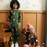 Child wearing Maxomora organic cotton green long-sleeve top with all over red fox print with matching pyjama trousers with a child sitting besides him wearing brown apple print top with pink trousers.