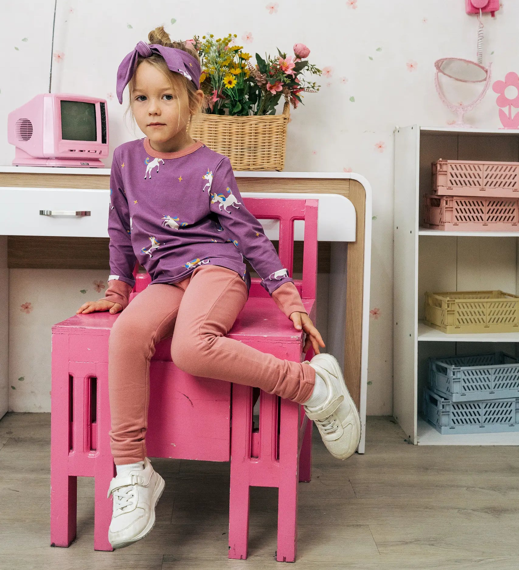 Child wearing the Maxomorra kids unicorns organic cotton long sleeve top with leggings. Purple top with  repeat unicorn print and light pink arm cuffs and binding on the neck. 