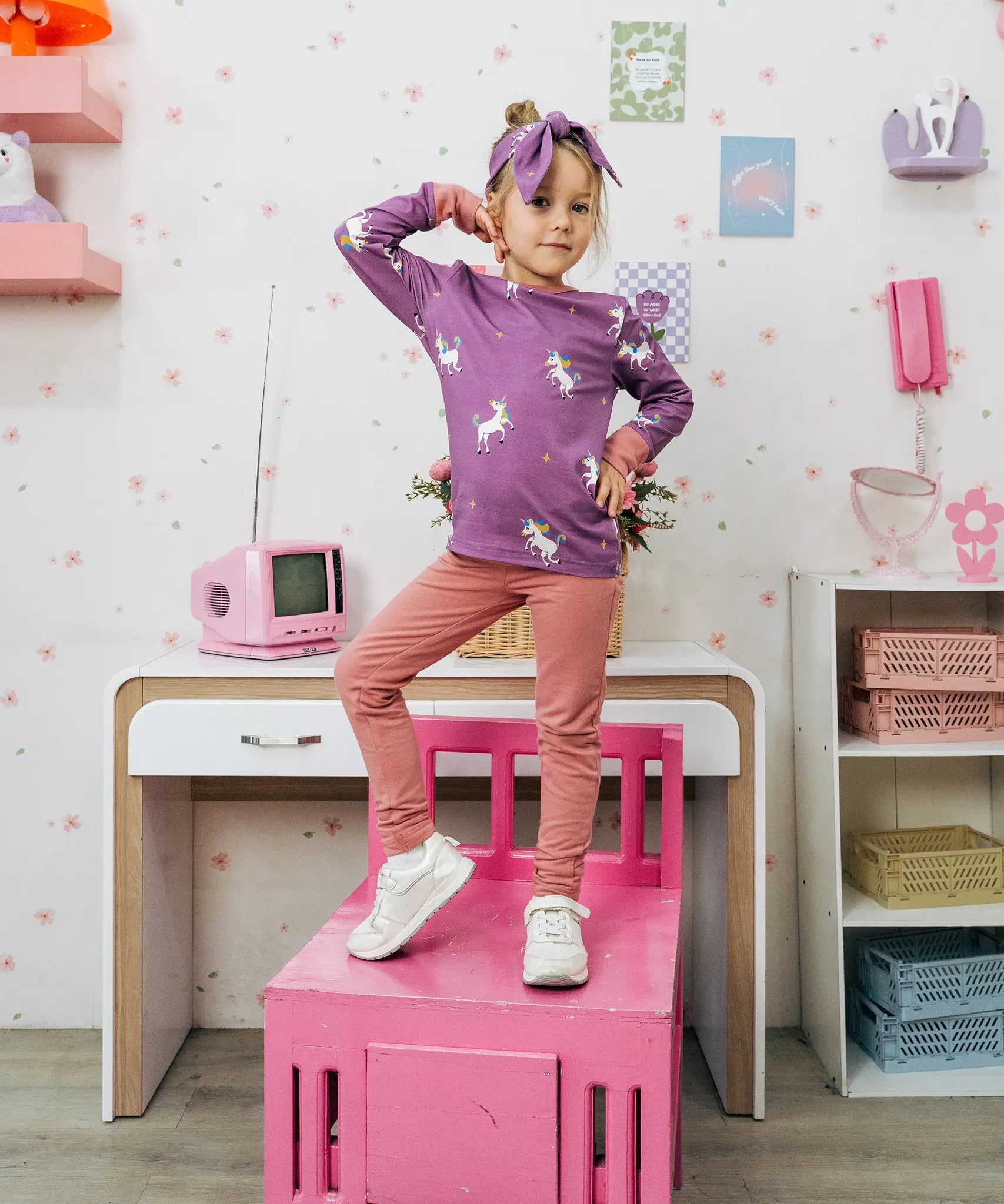 Child wearing the Maxomorra kids unicorns organic cotton long sleeve top with pink leggings. Purple top with  repeat unicorn print and light pink arm cuffs and binding on the neck. 