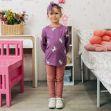 Child wearing the Maxomorra kids unicorns organic cotton long sleeve top with leggings. Purple top with  repeat unicorn print and light pink arm cuffs and binding on the neck. 