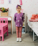 Child wearing the Maxomorra kids unicorns organic cotton long sleeve top with leggings. Purple top with  repeat unicorn print and light pink arm cuffs and binding on the neck. 
